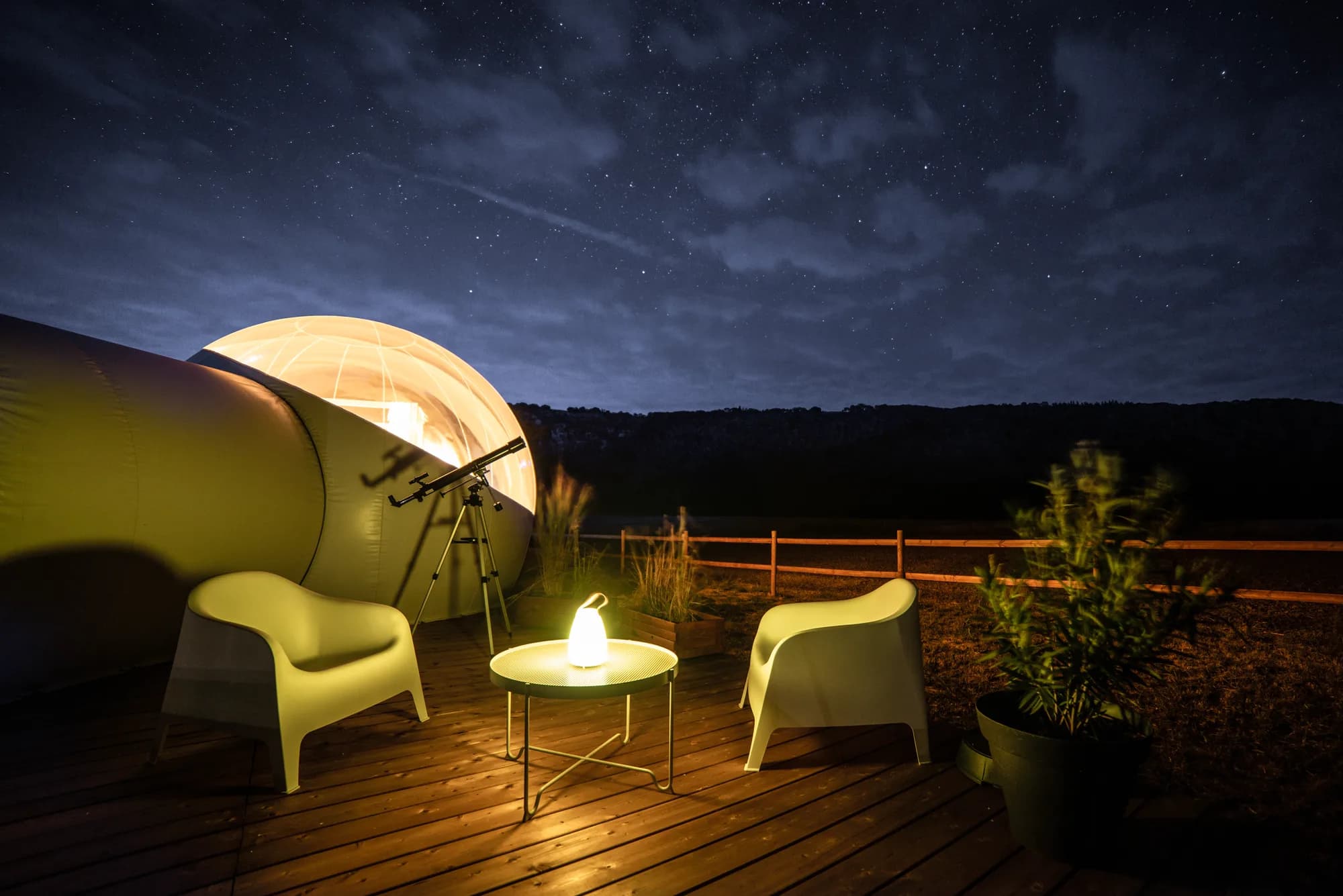 La bulle éclairée de nuit sur sa terrasse en bois, face aux collines de la Suisse Normande